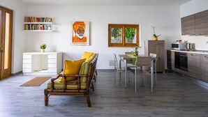 A modern living room with a sofa, dining table, and kitchen area. - Ca' delle Isole by Interhome (Stresa)