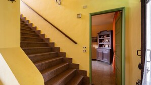 Un escalier menant à une cuisine, avec une porte verte et un meuble contenant de la vaisselle.
