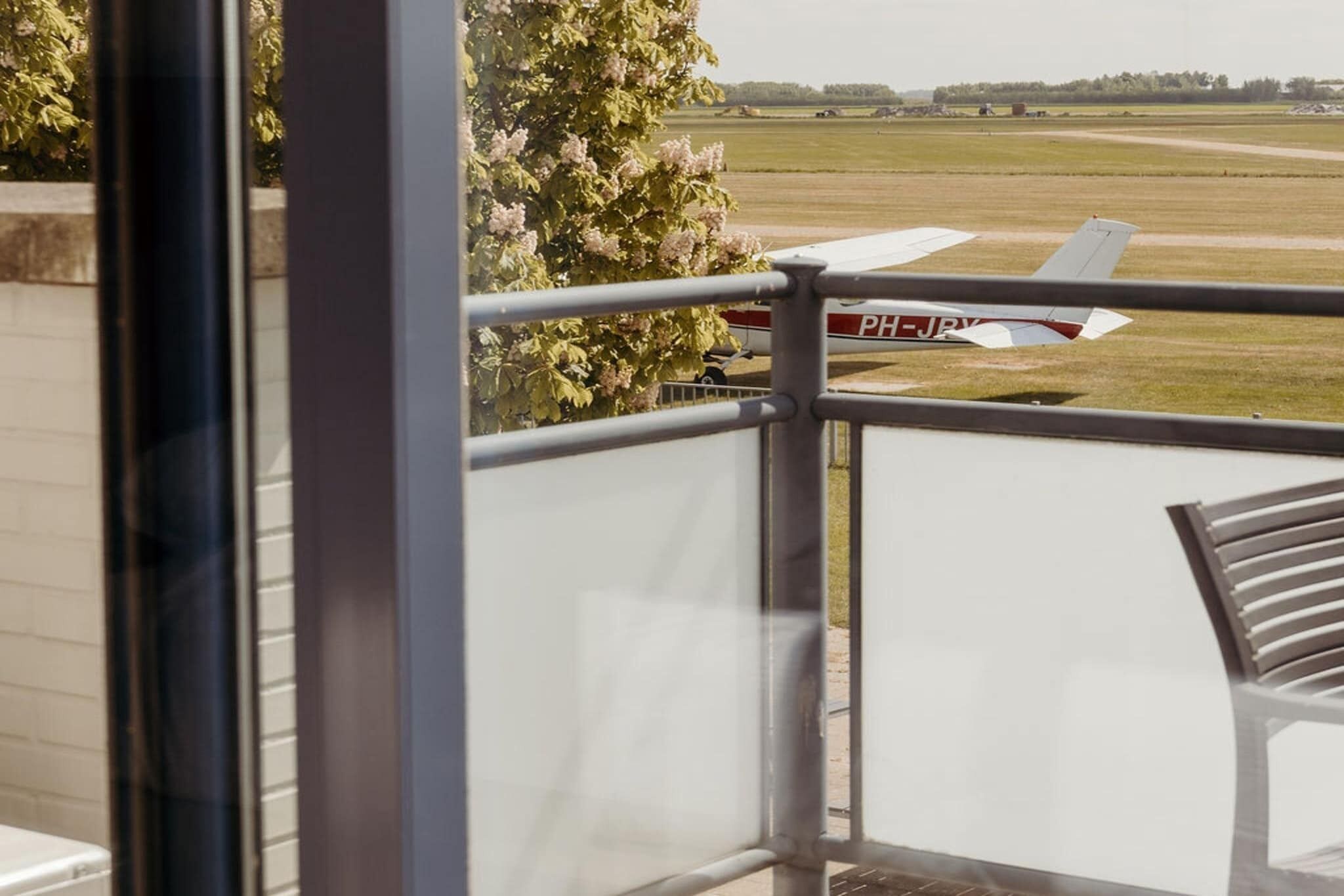 Blick auf ein Flugzeug auf einer Startbahn vom Balkon mit Metallgeländer.