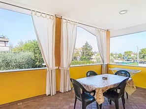 A balcony with yellow walls, a table, two chairs, and white curtains.