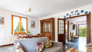 A living room with a sofa, a dining table, and chairs. There is a wooden cabinet and a door leading to another room. - La Casetta by Interhome (Diano Marina)