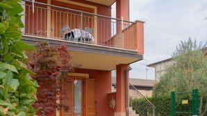 Un bâtiment à deux étages doté d’un balcon, d’un escalier et d’un jardin clos.