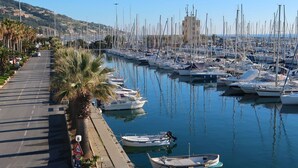 A marina with numerous boats docked along a waterfront promenade lined with palm trees. - Apartment Sara by Interhome (Santo Stefano al Mare)