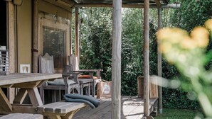 Une terrasse en bois, agrémentée de tables de pique-nique et de bancs, entourée d’une végétation luxuriante.