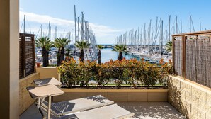 Ein Balkon mit Blick auf einen Jachthafen, der mehrere Segelboote und Palmen zeigt.