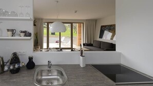 A modern kitchen with a built-in stove, a sink, and a window overlooking a backyard.