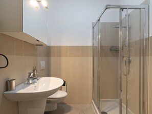 Une salle de bain moderne avec une douche à parois de verre, un lavabo blanc et des toilettes.