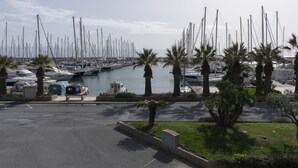 Een jachthaven met vele zeilboten, palmbomen en een heldere lucht.