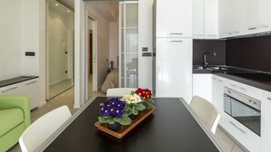 Een moderne keuken met witte kasten, een zwart aanrecht en een eethoek met een tafel en stoelen.