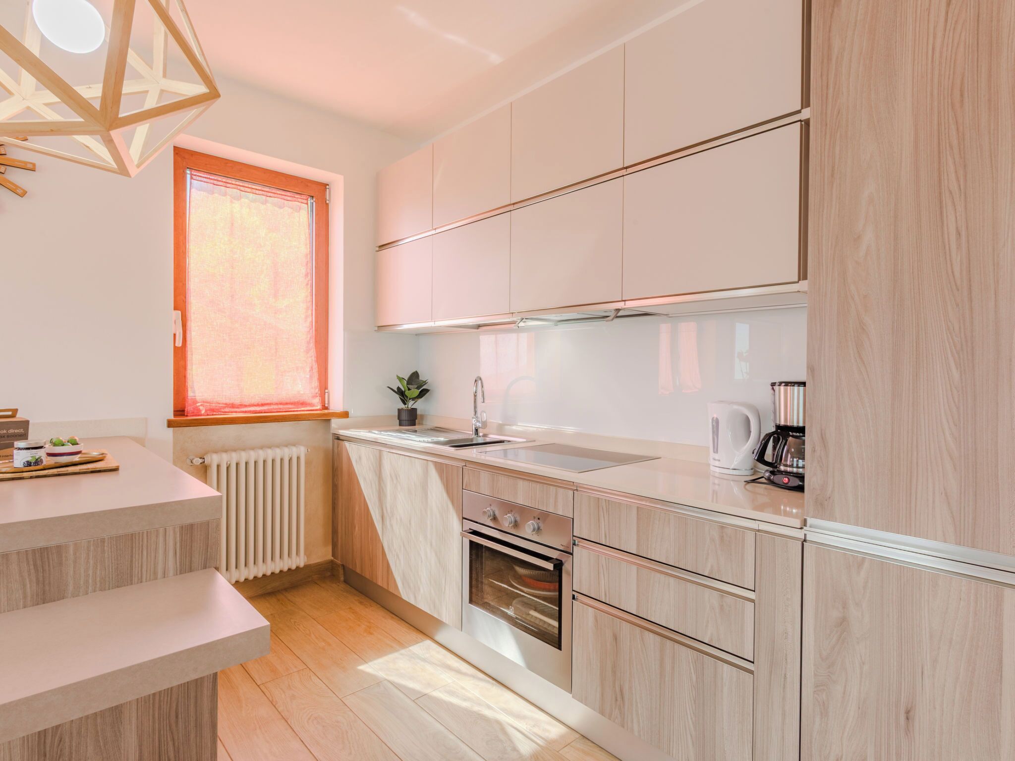 Eine moderne Küche mit Einbauofen, Spüle und einem Fenster mit Jalousien.