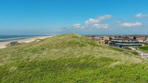A coastal town with a prominent hill, beach, and modern buildings. - Wijde Blick 205 apartment with balcony (Callantsoog)