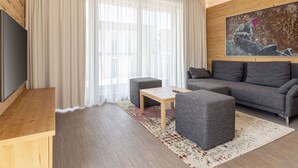 Una sala moderna con un sofá gris, una mesita y un televisor montado en un mueble de madera.