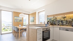 Una cocina moderna con armarios de madera, horno integrado y un amplio ventanal con vistas al exterior.