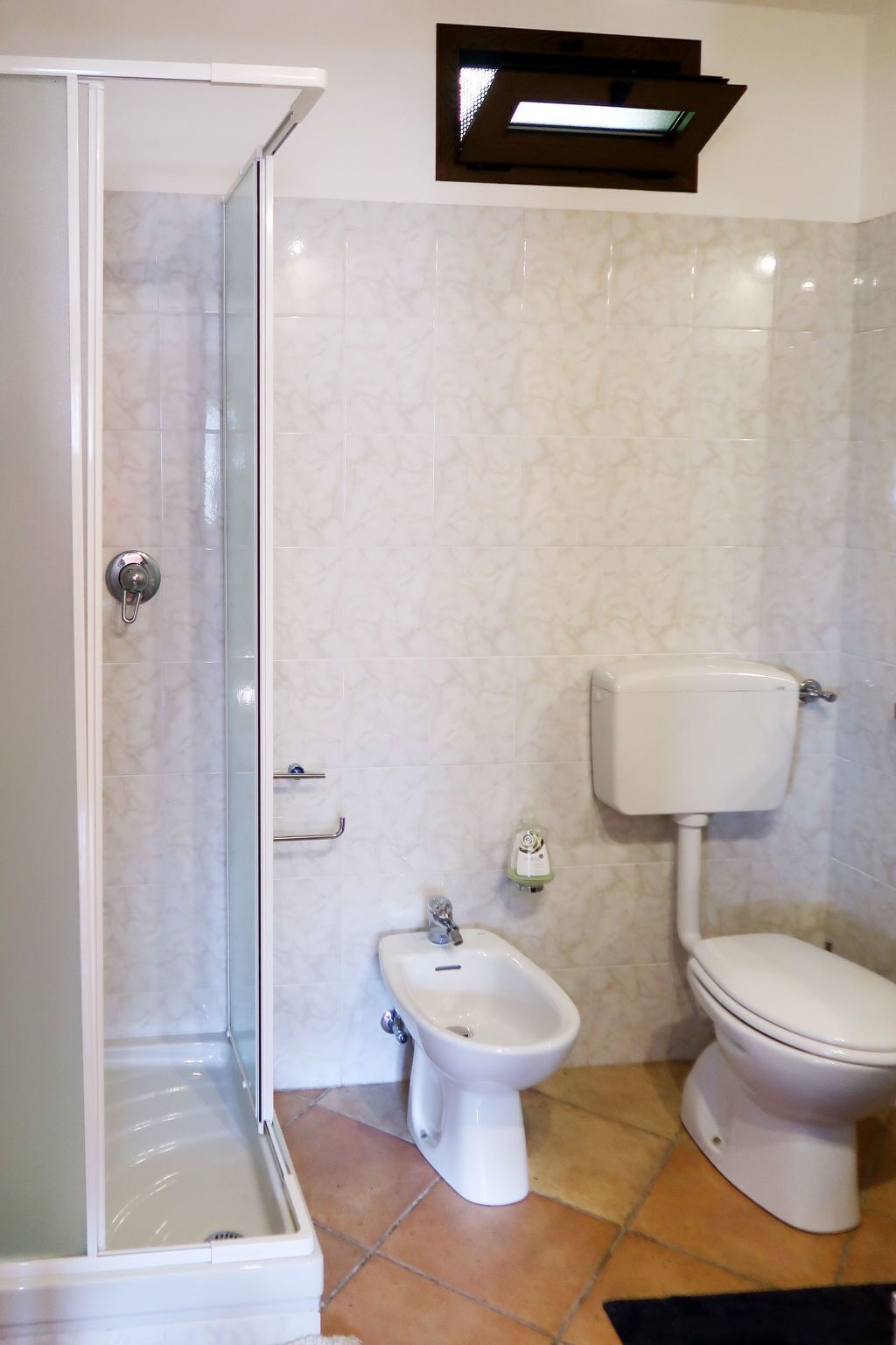 A bathroom with a glass-enclosed shower, a bidet, and a toilet.