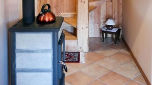 Eine Holztreppe mit rustikalem Interieur, ein Kaminofen und ein kleiner Tisch mit einer Lampe.