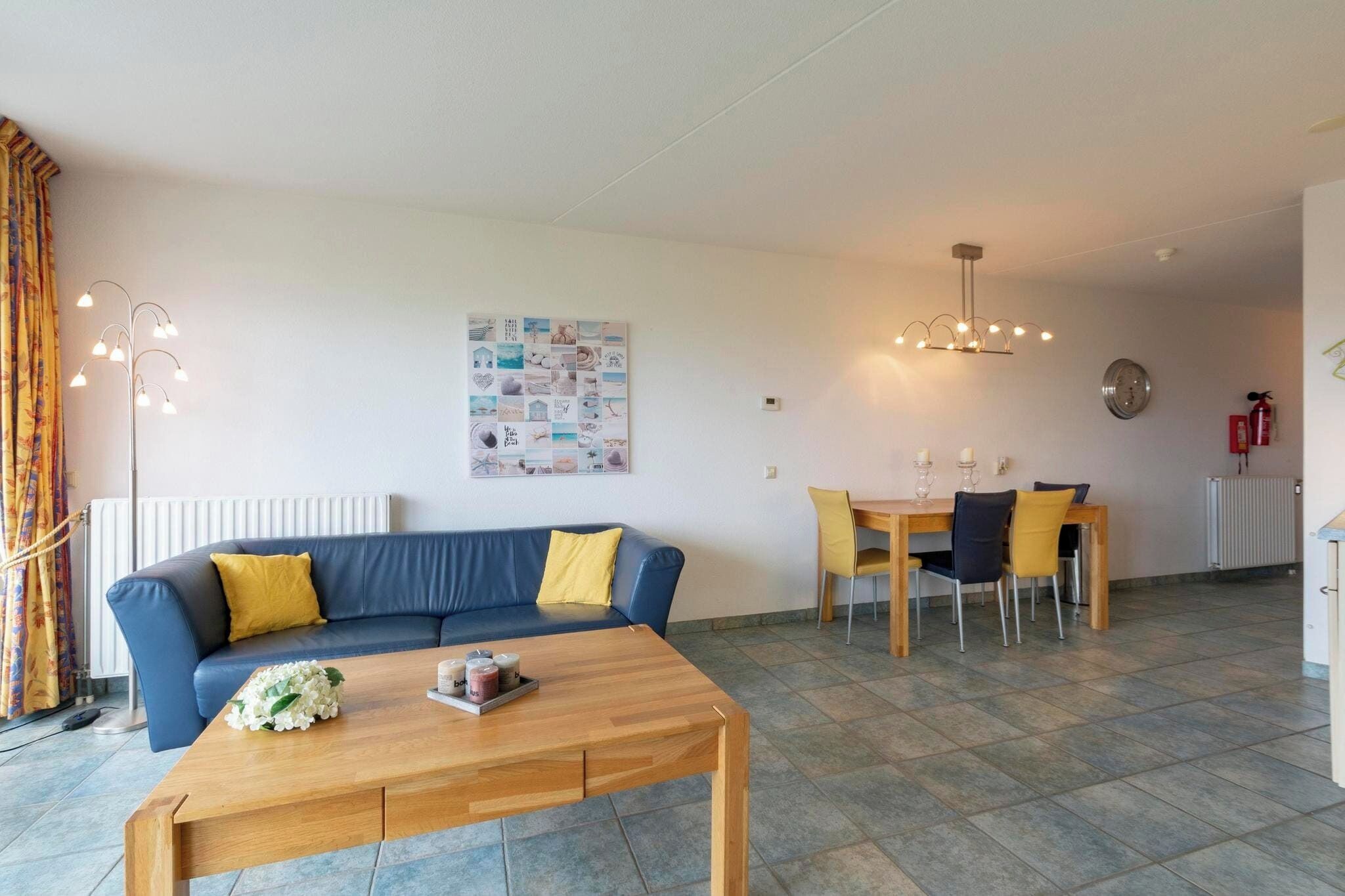 Ein Wohnzimmer mit blauem Sofa, Holztisch und einem Essbereich mit Holztisch und Stühlen.