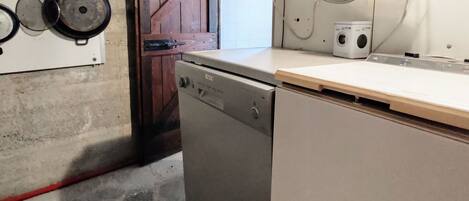 A compact kitchen with a dishwasher, a wooden door, and a wall-mounted stove.