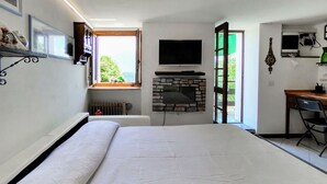 A bedroom with a bed, a fireplace, a desk, and a TV. - Baita dei Nonni by Interhome (Gravedona)