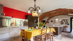 A dining area with a yellow tablecloth, wooden chairs, and a brick archway. - Vacation home Carla by Interhome (Cortazzone)
