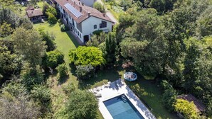 An aerial view of a house with a swimming pool, surrounded by lush greenery and trees. - Vacation home Carla by Interhome (Cortazzone)