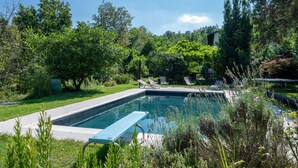 A rectangular swimming pool with a blue edge, surrounded by lush greenery and trees. - Vacation home Carla by Interhome (Cortazzone)