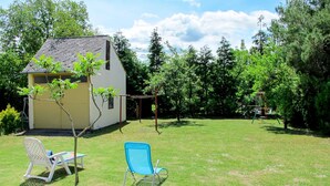 A small house with a sloped roof and a garden area with two lawn chairs and a swing set. - Violett by Interhome (Balatonmariafurdo)