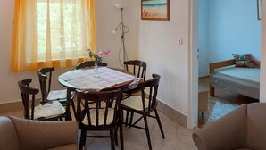 A dining area with a table, chairs, and a vase of flowers. There is a window with curtains, a lamp, and a painting on the wall. - Violett by Interhome (Balatonmariafurdo)