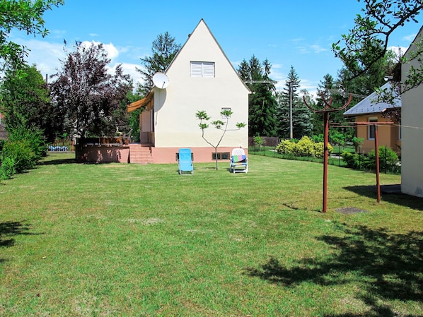 A house with a sloped roof, a satellite dish, and a small tree in the front yard.