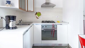 A modern kitchen with white cabinetry, a stainless steel range hood, a coffee maker, and a gas stove. - Madal (GRV399) by Interhome (Gravedona)