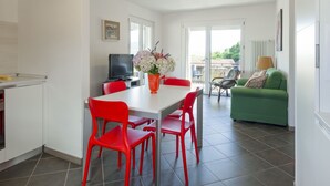 A modern kitchen with a dining area, red chairs, and a green sofa. - Madal (GRV399) by Interhome (Gravedona)