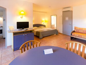 Cozy retreat with a bed, flat-screen TV, and kitchenette, perfect for a comfortable stay.