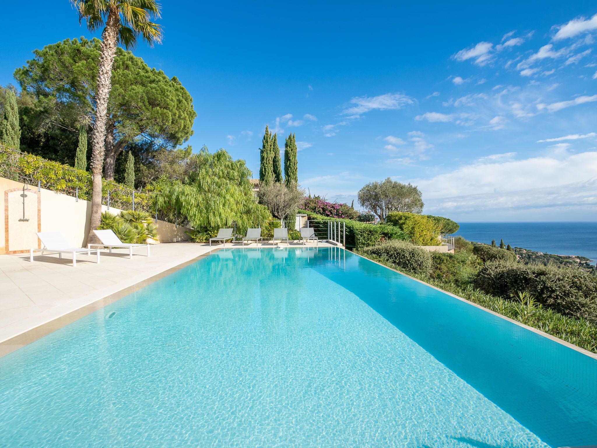 Ein klares, blaues Schwimmbecken mit Liegestühlen und Blick auf das Meer.