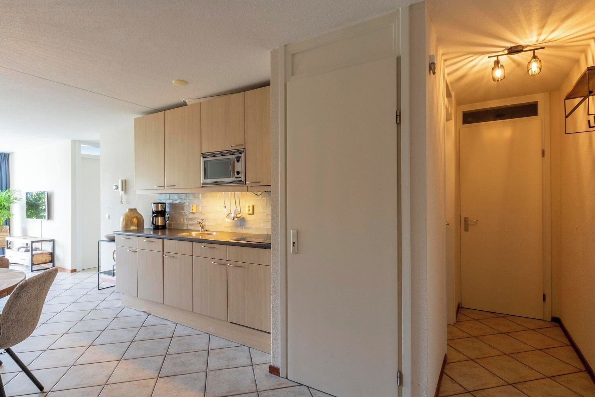 A modern kitchen with light wood cabinets, a microwave, and a sink.