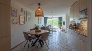 Una cocina moderna con comedor, ventanas amplias y una lámpara colgante.