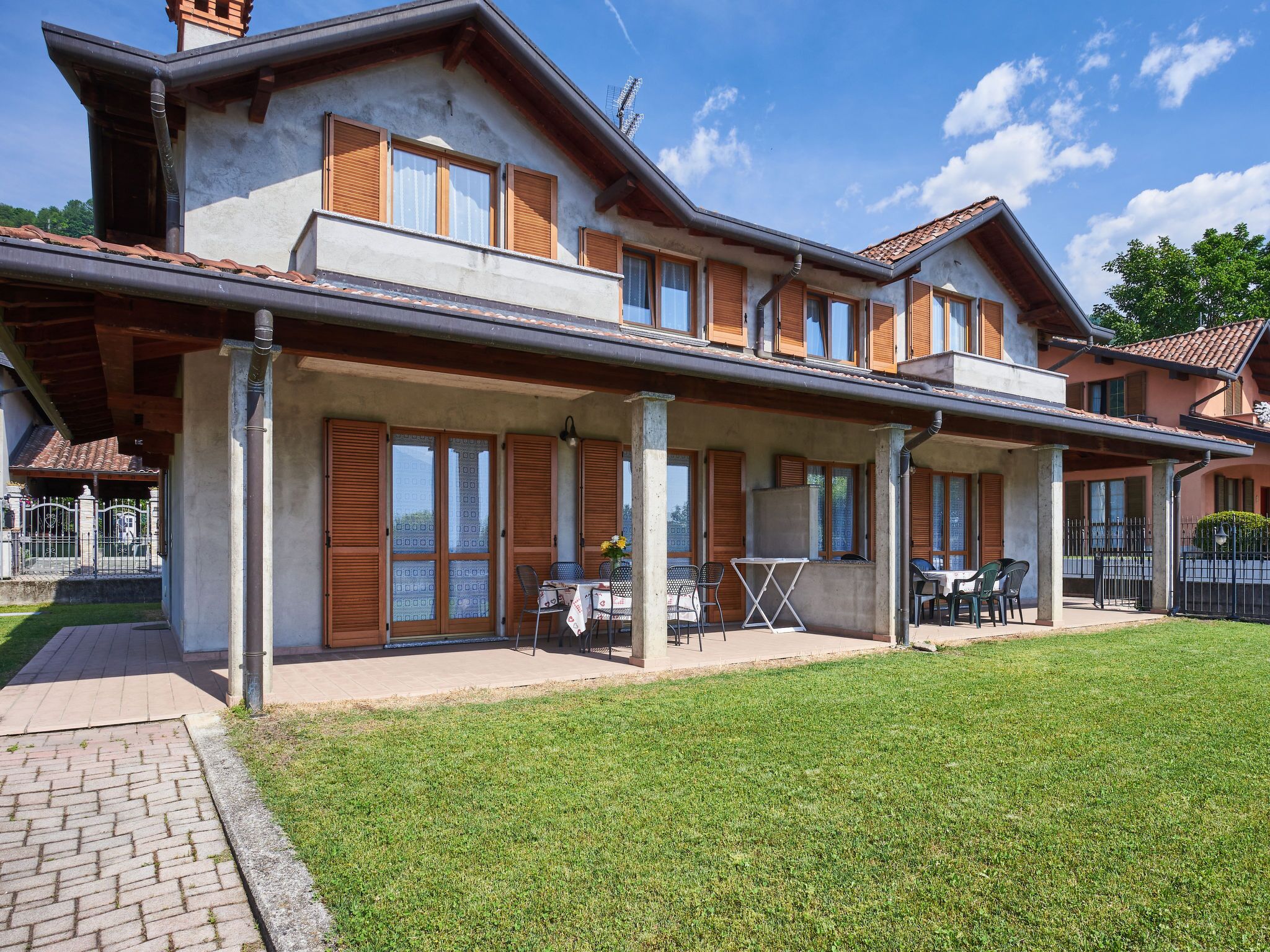 A two-story house with a covered patio area, a small garden, and a paved walkway.