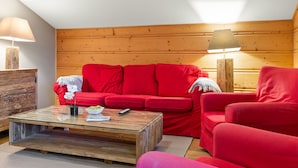 Ein gemütliches Zimmer mit einem roten Sofa, einem Glastisch und Holzwänden.