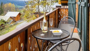 Ein Balkon mit Tisch und Stühlen, einer Champagnerflasche und einem Glas.