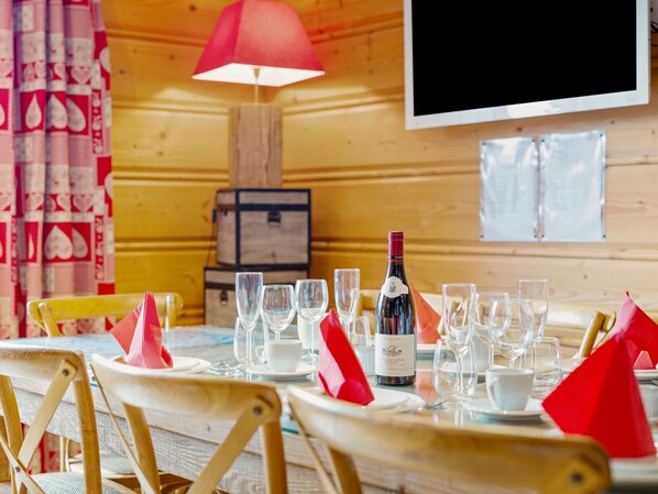 A dining table set with wine glasses, a bottle of wine, and red napkins.