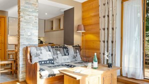Una habitación acogedora con un sofá de madera, una mesita de madera y un pilar de piedra.