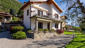 Une maison à deux étages avec un balcon, des fondations en pierre et une allée gravillonnée.