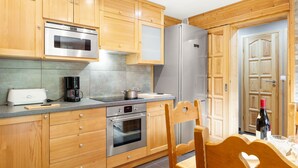 Eine moderne Küche mit Holdekor-Schränken, Edelstahlgeräten und einem Essbereich mit Holztisch und Stühlen.