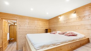 Ein Zimmer aus Holz mit einem Bett, einem kleinen Tisch und einem Kleiderschrank.