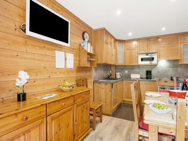 Une cuisine moderne avec des meubles en bois, un four encastré et un coin repas comprenant une table et des chaises.