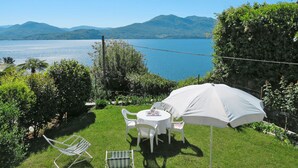 A patio with a table and chairs, an umbrella, and a view of a lake and mountains.