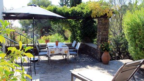 Eine Terrass mit Tisch, Stühlen, einer Liege und einem Blumentopf.