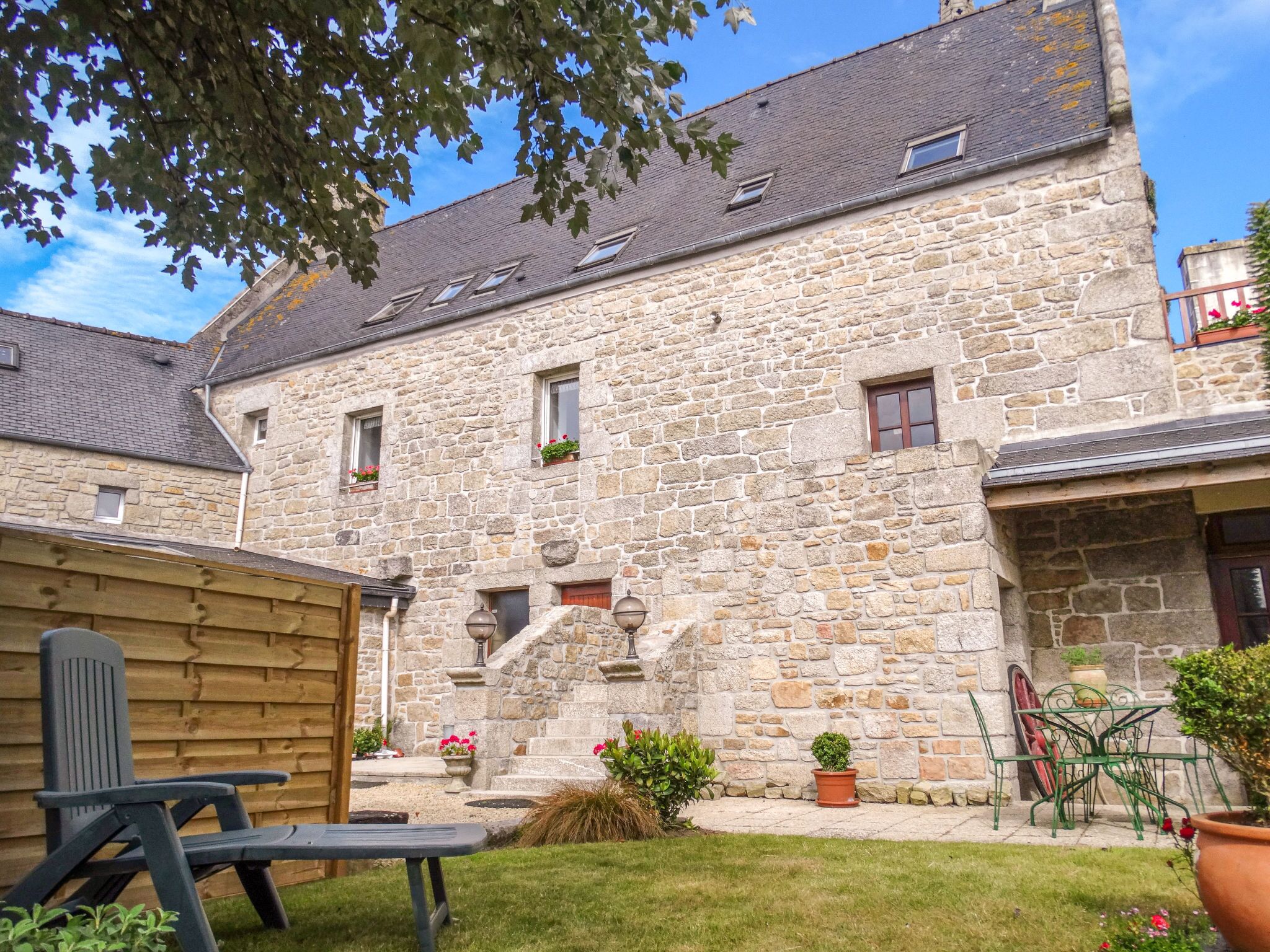 A stone building with a courtyard, a wooden bench, and potted plants.