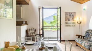 Ein Essbereich mit Tisch für zwei Personen, einer Couch und Blick ins Freie.