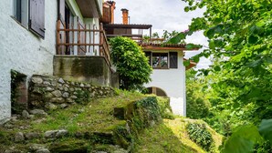 Eine rustikale Steintreppe führt zu einem weißen Gebäude mit einem hölzernen Balkon.