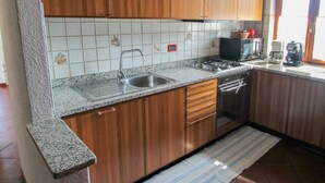 Eine Küche mit Holzausstattung, einem Edelstahlspülbecken, einem Gasherd und einer Kaffeemaschine.
