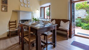 Un comedor con una mesa de madera dispuesta para cuatro, un banco y vista a un jardín a través de un ventanal abierto.